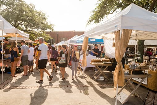 Winter Park Farmers Market with vendor tents, shoppers, local goods, and a sunny outdoor market walkway.